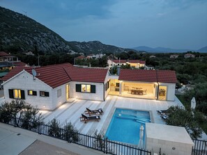 A modern house with a swimming pool, outdoor seating, and a view of the surrounding landscape. - Resort Moja Stina - Villa Maslina (Seoca)