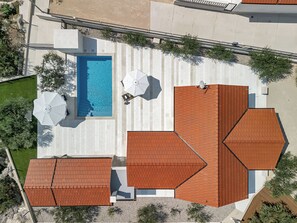 Vue aérienne d’une propriété dotée d’une piscine, d’un espace salon extérieur et d’un patio couvert.