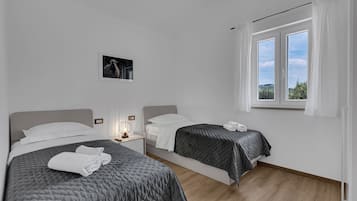 Een moderne hotelkamer met twee bedden, een groot raam en uitzicht op de omgeving.