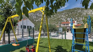Une aire de jeux avec des balançoires, un toboggan et une structure d’escalade.