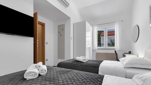 Une chambre d’hôtel moderne avec deux lits, une grande fenêtre offrant une belle vue et un téléviseur à écran plat fixé au mur.