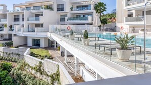 Un immeuble résidentiel moderne à plusieurs étages, doté de balcons, d’une piscine et d’espaces de détente en plein air.