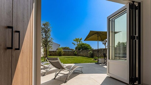 A modern patio with a glass door leading to a backyard. - Holiday home with lush garden in Loix (Loix)