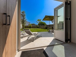 A modern patio with a glass door leading to a backyard. - Holiday home with lush garden in Loix (Loix)