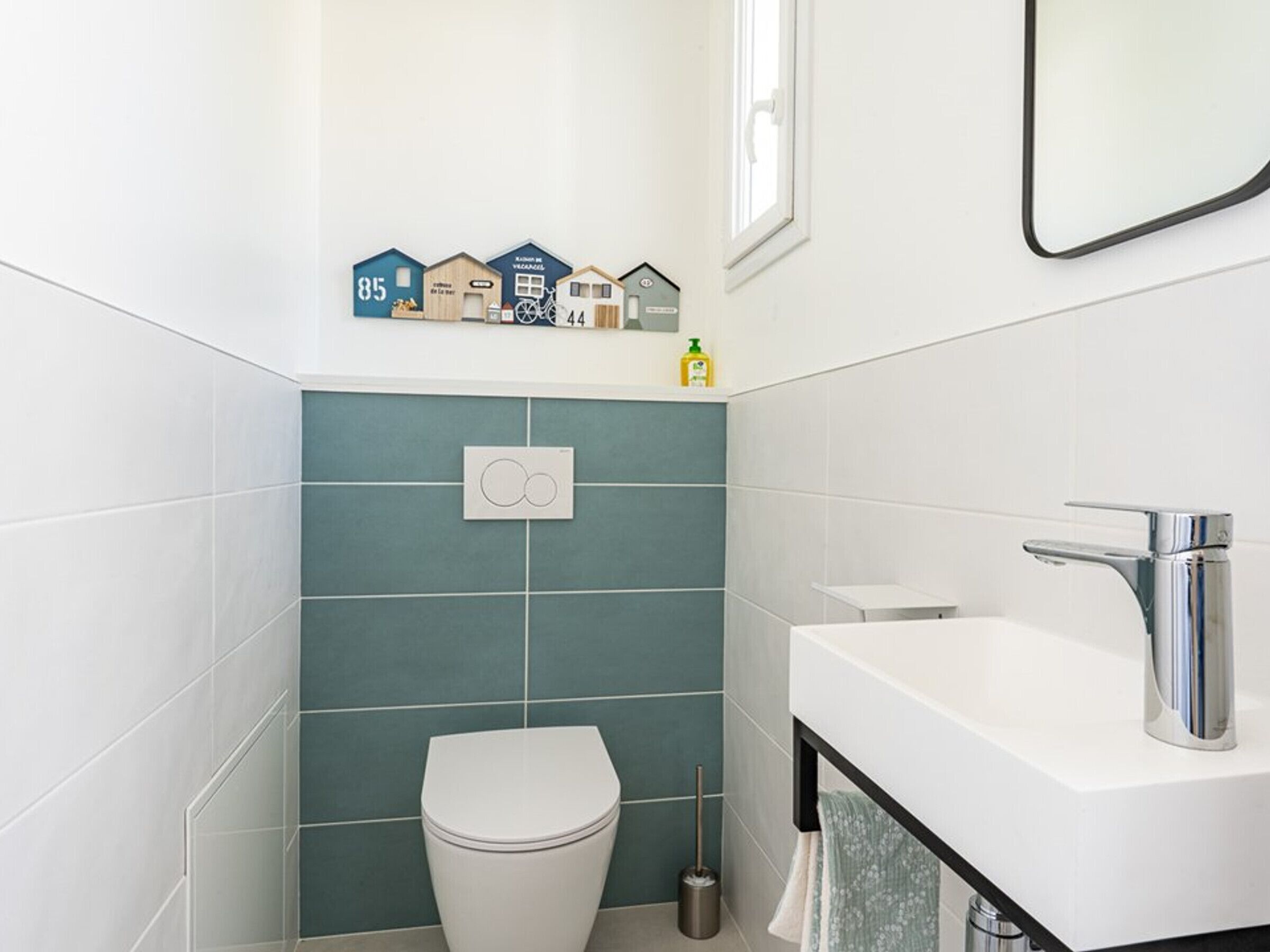 A modern bathroom with a toilet, sink, and a wall-mounted toilet paper holder.
