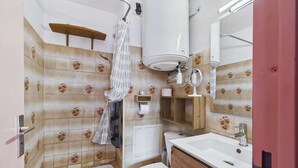 A bathroom with a bathtub, toilet, sink, and a shower curtain. - 2-room apartment with loggia in Marseillan-Plage (Marseillan-Plage)