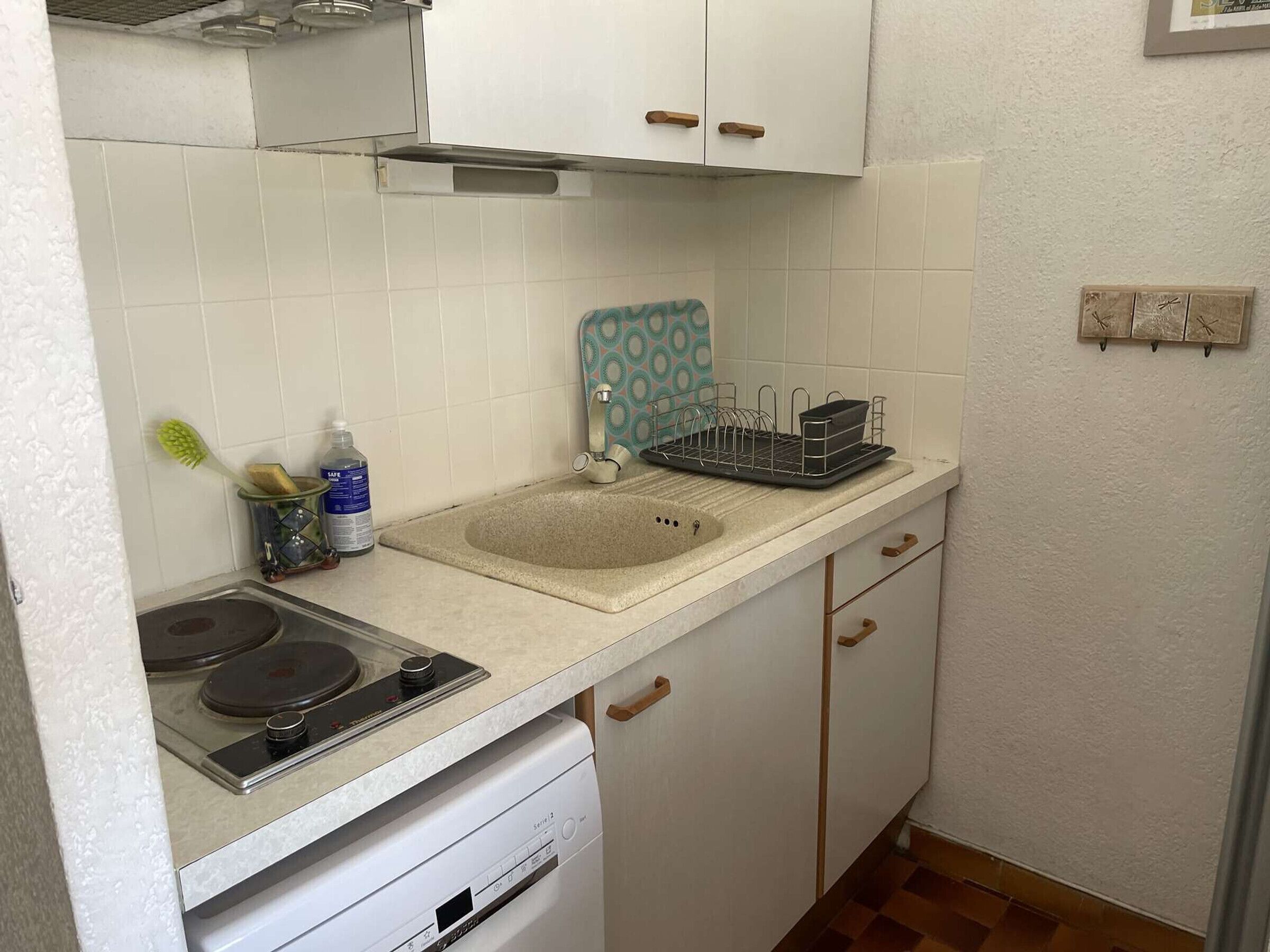 Une cuisine de taille réduite, équipée d’un évier, d’une cuisinière et d’un lave-vaisselle.