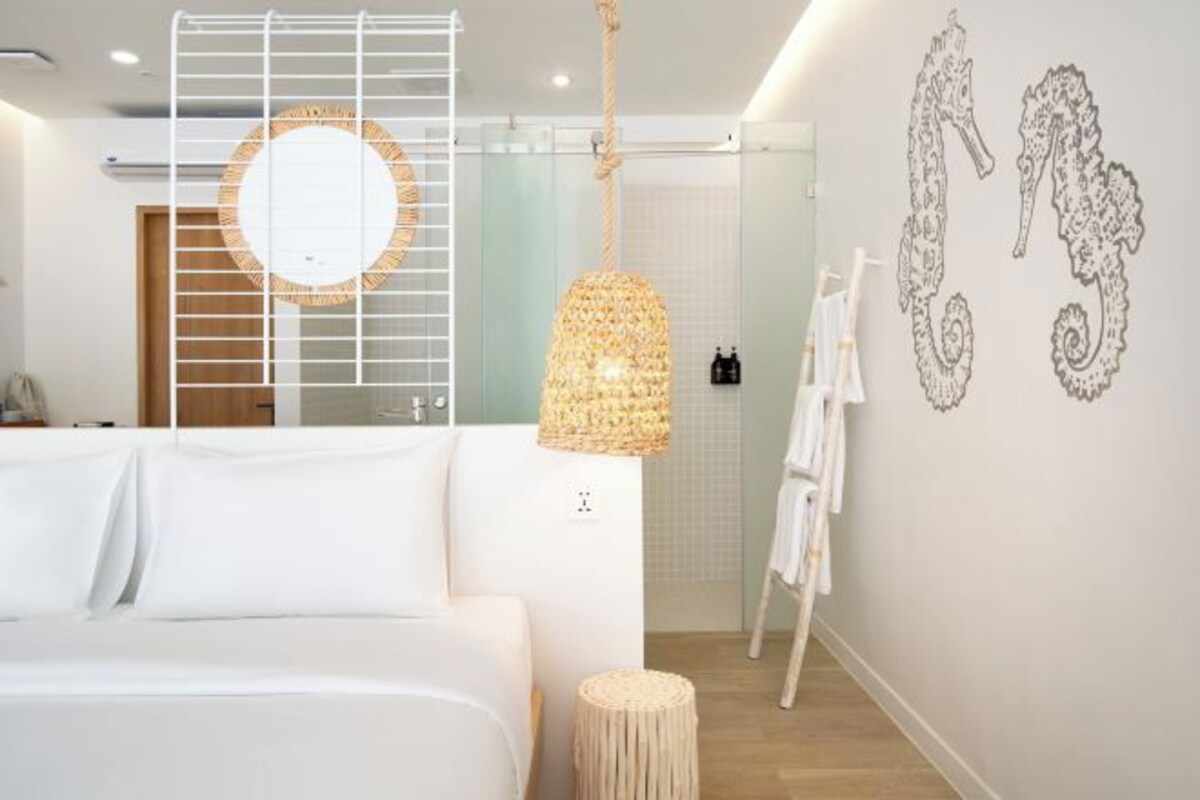Una habitación de hotel moderna con una cama grande, una lámpara colgante y detalles decorativos en la pared.