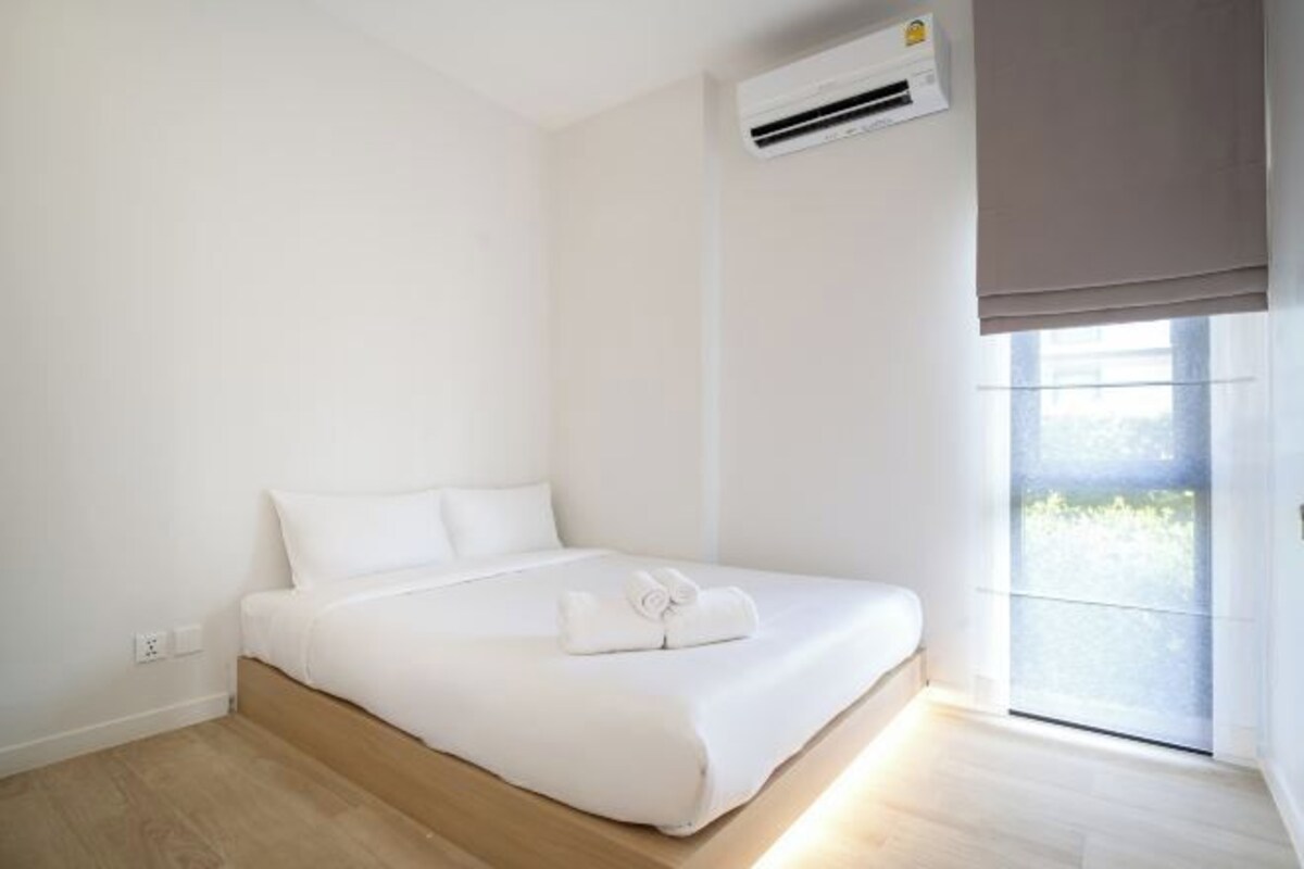 Una habitación de hotel moderna con cama, ventana con vistas y equipo de aire acondicionado.
