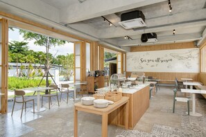 Un restaurant moderne doté d’une vaste salle à manger ouverte, de touches de bois et d’une vue sur l’extérieur.