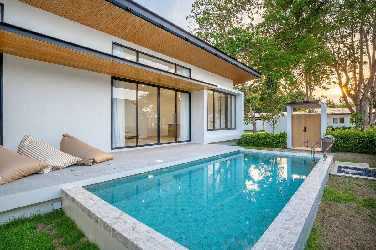 A modern house with a swimming pool, large sliding glass doors, and a wooden deck.
