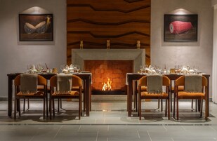 Un comedor con chimenea, techo de madera y cuadros en las paredes.