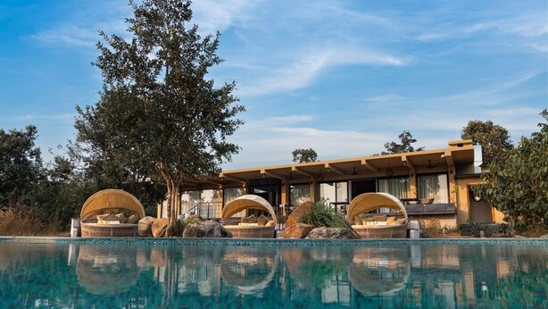 Un complexe hôtelier moderne doté d’une piscine, d’espaces de détente en plein air et d’un grand arbre.
