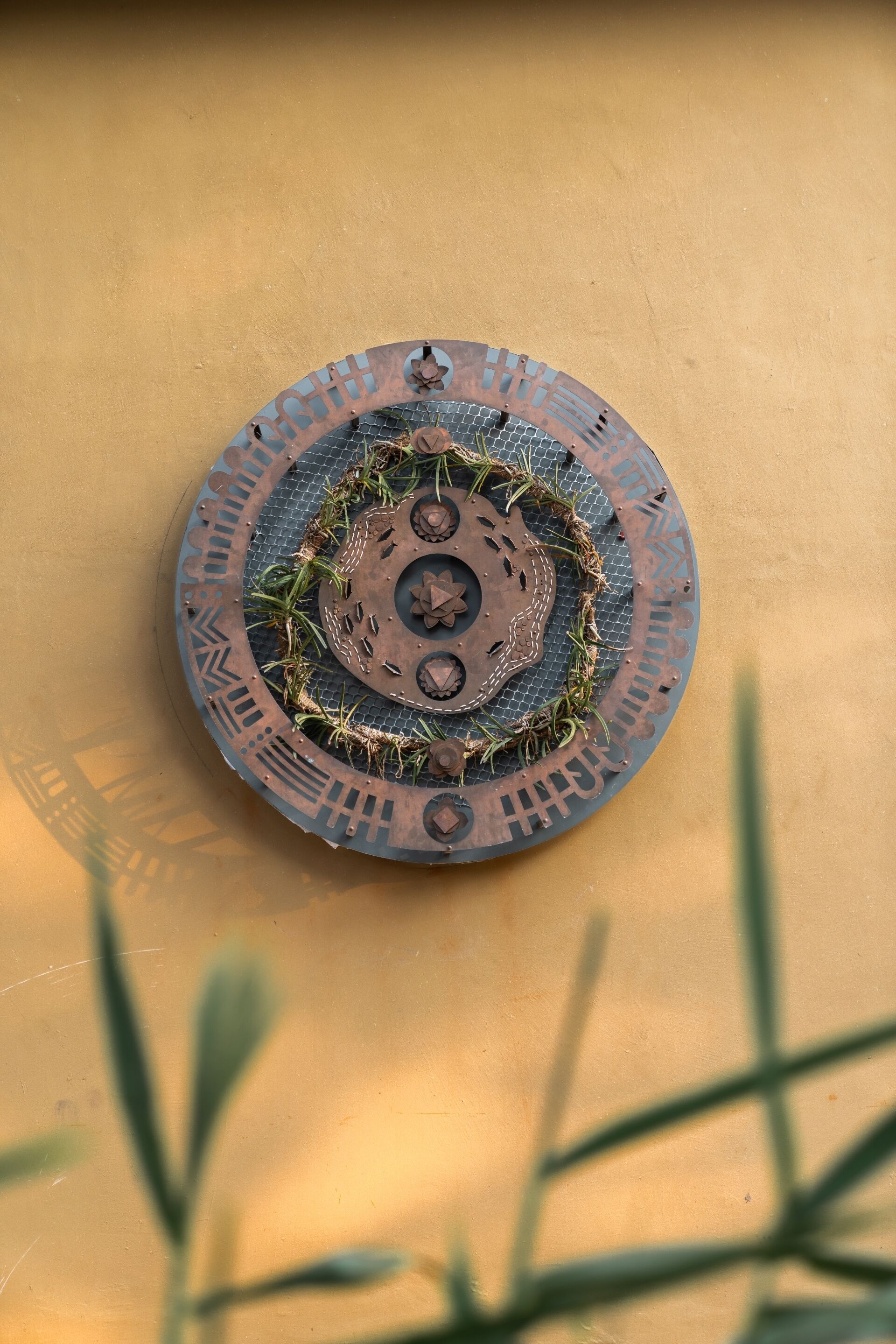 Un objeto metálico circular con diseños intrincados y un orificio central, sobre una superficie amarilla.