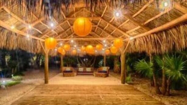 An indoor wooden structure with a thatched roof, multiple hanging spherical lights, and a central seating area. - Private Island Suite w/ Terrace & Balcony @Islamorada - Coconut Palm Suite (Islamorada)