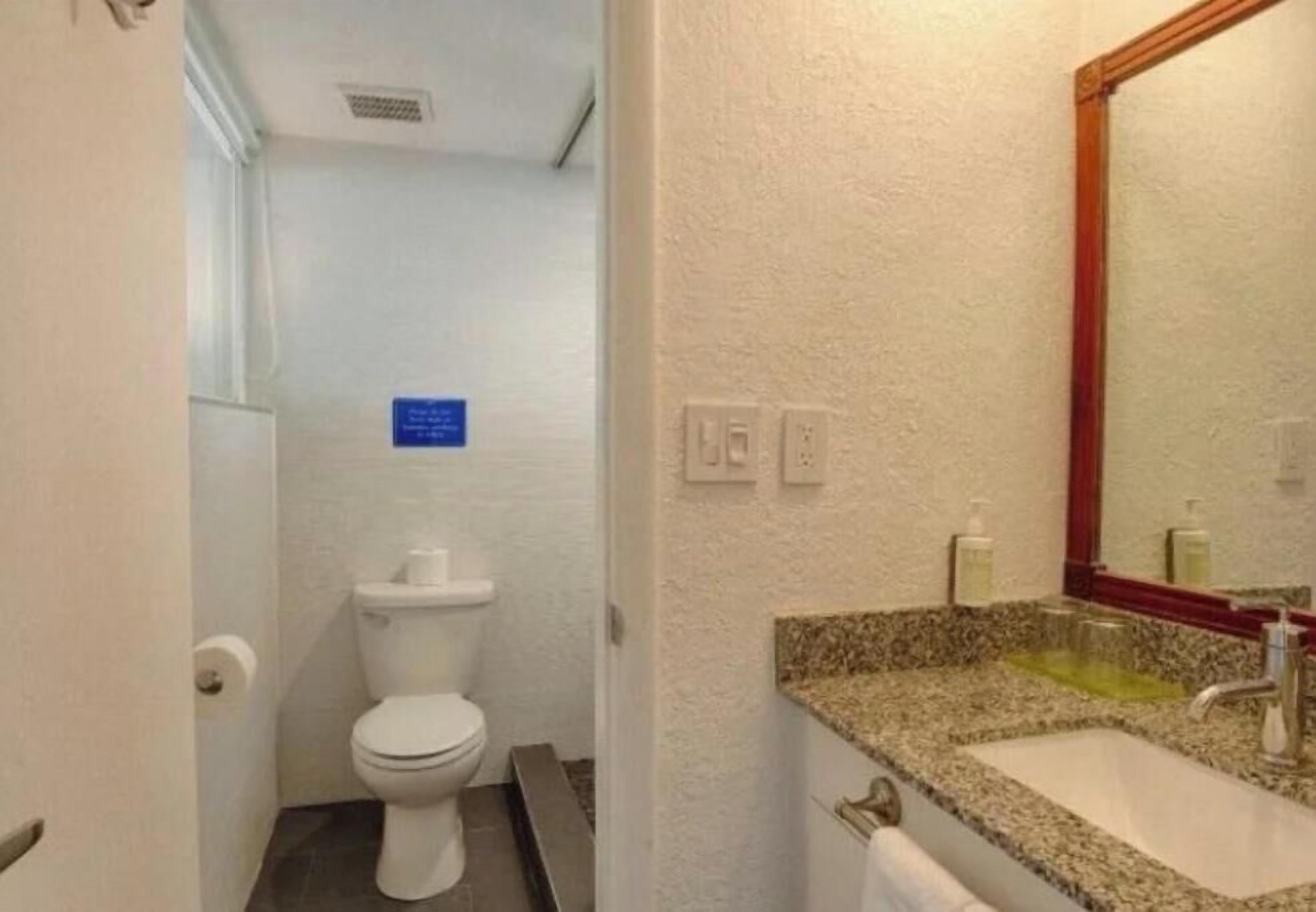 Un baño pequeño con inodoro, lavamanos y espejo.