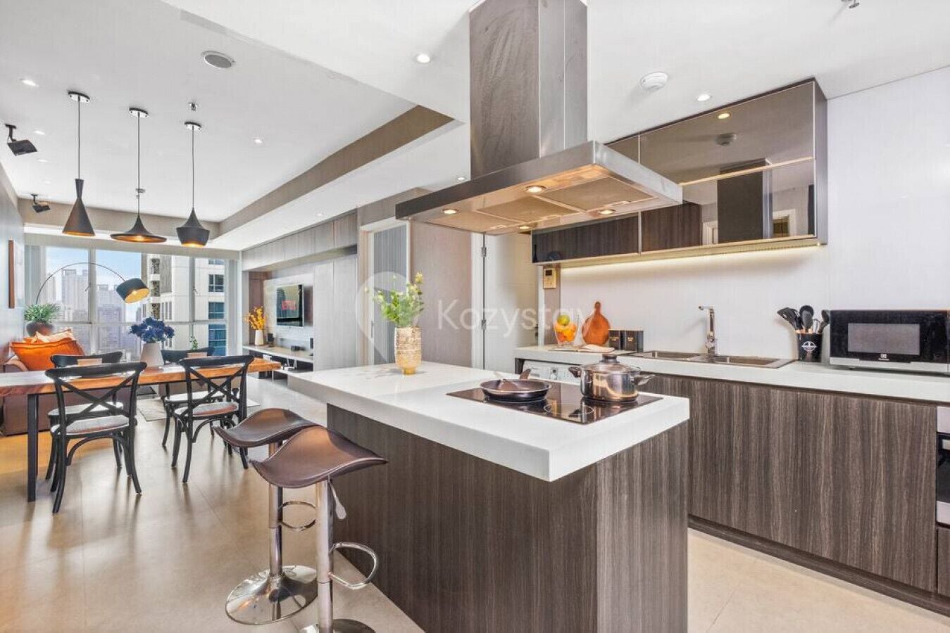 A modern kitchen with a central island, pendant lighting, and a large window providing natural light.