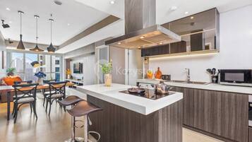 A modern kitchen with a central island, pendant lighting, and a large window providing natural light.