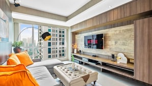 A modern living room with a large TV, a sofa, and a coffee table. - Jade by Kozystay - Kuningan (Jakarta)