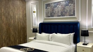 Ein modernes Schlafzimmer mit einem großen Bett, zwei Nachttischen, einem Holzschrank und einem großen abstrakten Gemälde an der Wand.