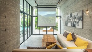 A modern interior with a large window, a wooden table, a sofa with yellow cushions, and a painting on the wall.