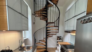 Una cocina moderna con una escalera espiral, electrodomésticos de acero inoxidable y suelo de madera.