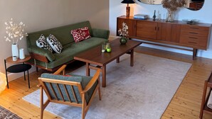 Una sala de estar con un sofá verde, una mesa de centro de madera y una lámpara colgante.