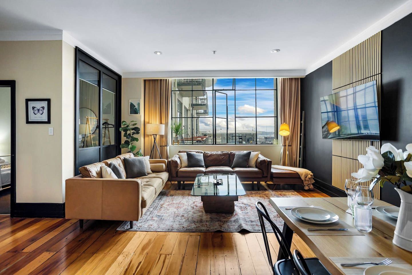 A modern living room with a sofa set, a coffee table, and a dining area with a table set for two.