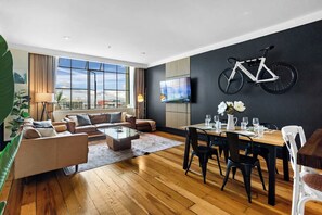 A modern living room with a sofa set, a coffee table, and a dining area with chairs and a table set for a meal.