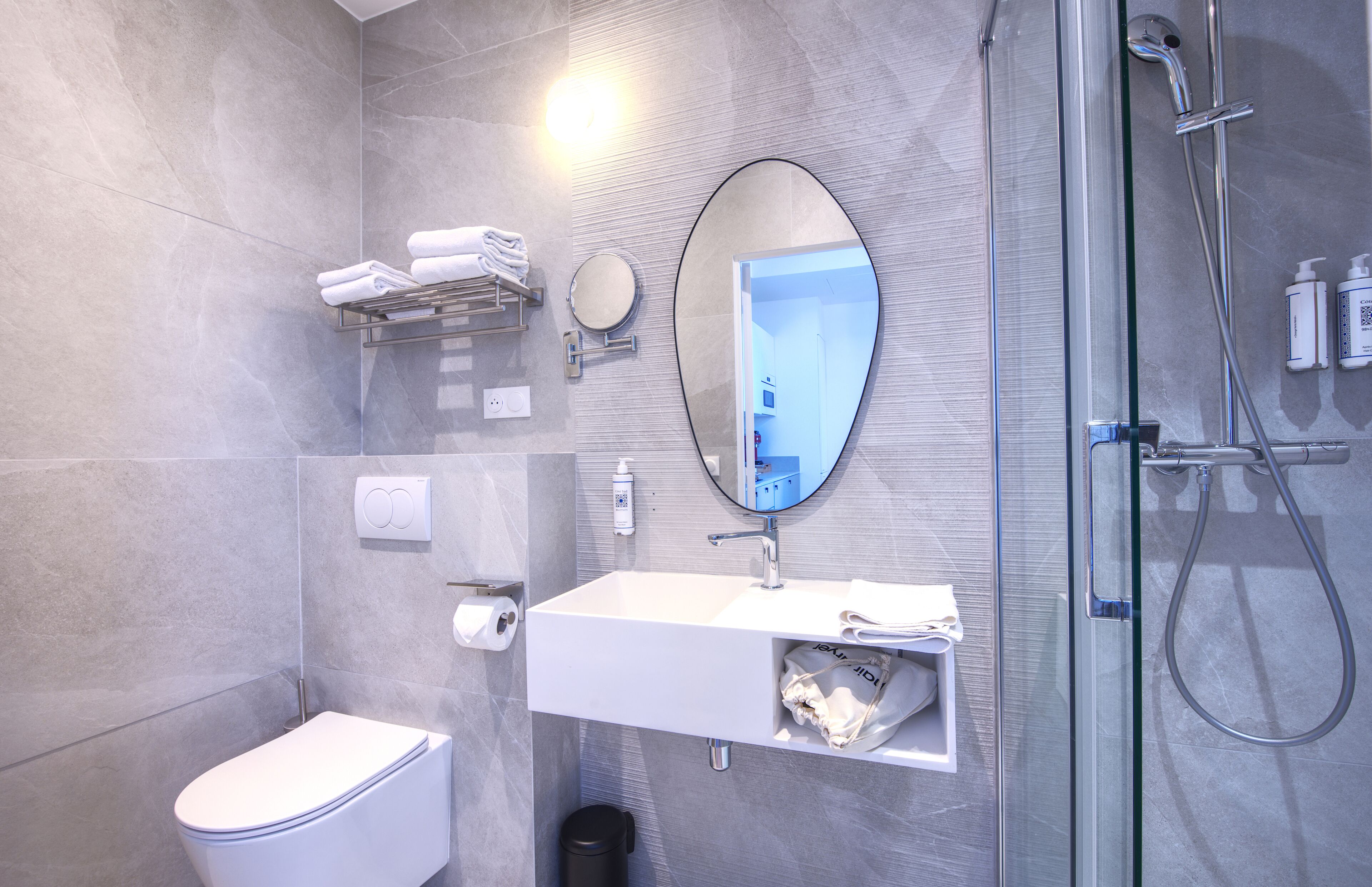 Un baño moderno con ducha de vidrio, lavamanos blanco con espejo y un inodoro.