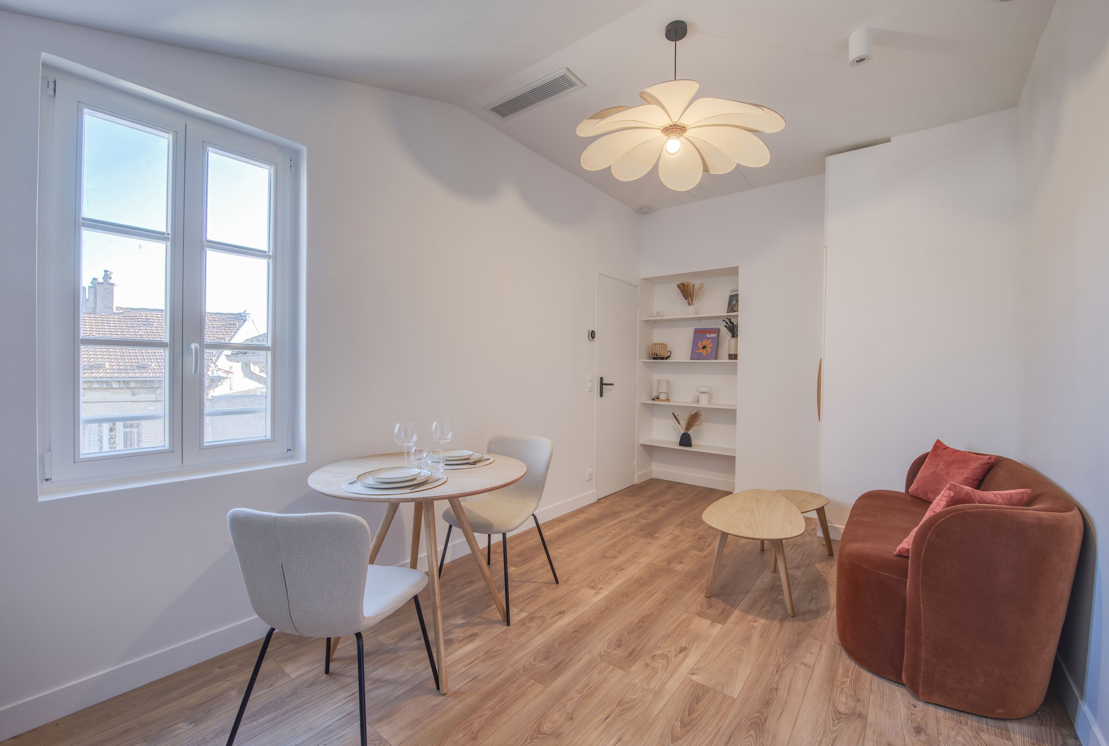 Una sala de estar moderna con comedor, un sofá y una lámpara en el techo.