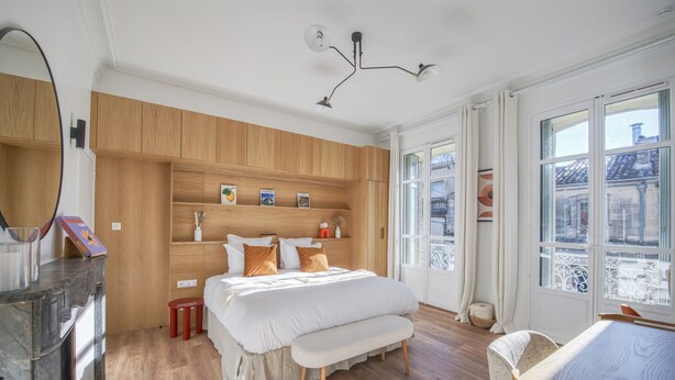 A bedroom with a wooden wardrobe, a bed with white bedding, a bench, and a bedside table. - Villa Victor Hugo by Odomo (Avignon)