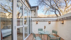 A patio with a wooden deck, a round table, and four chairs. - Villa Victor Hugo by Odomo (Avignon)