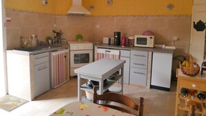 A compact kitchen with a dining table, white cabinets, and a microwave.