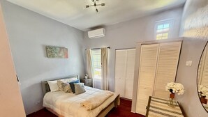 A bedroom with a bed, a nightstand, a dresser, a mirror, and a window with curtains. - Cozy 2-bedroom apartment in enjoyable Sandys with AC, WiFi (Sandys)
