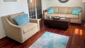 A living room with a beige sofa, a beige armchair, a wooden coffee table, and a blue patterned rug. - Cozy 2-bedroom apartment in enjoyable Sandys with AC, WiFi (Sandys)