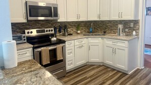 A modern kitchen with white cabinets, stainless steel appliances, and a herringbone tile backsplash. - Cozy 2-bedroom apartment in enjoyable Sandys with AC, WiFi (Sandys)