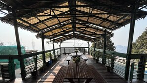 An outdoor covered area with picnic tables and potted plants. - Orangepetal Comfort Himalayan Resort (Darjeeling)