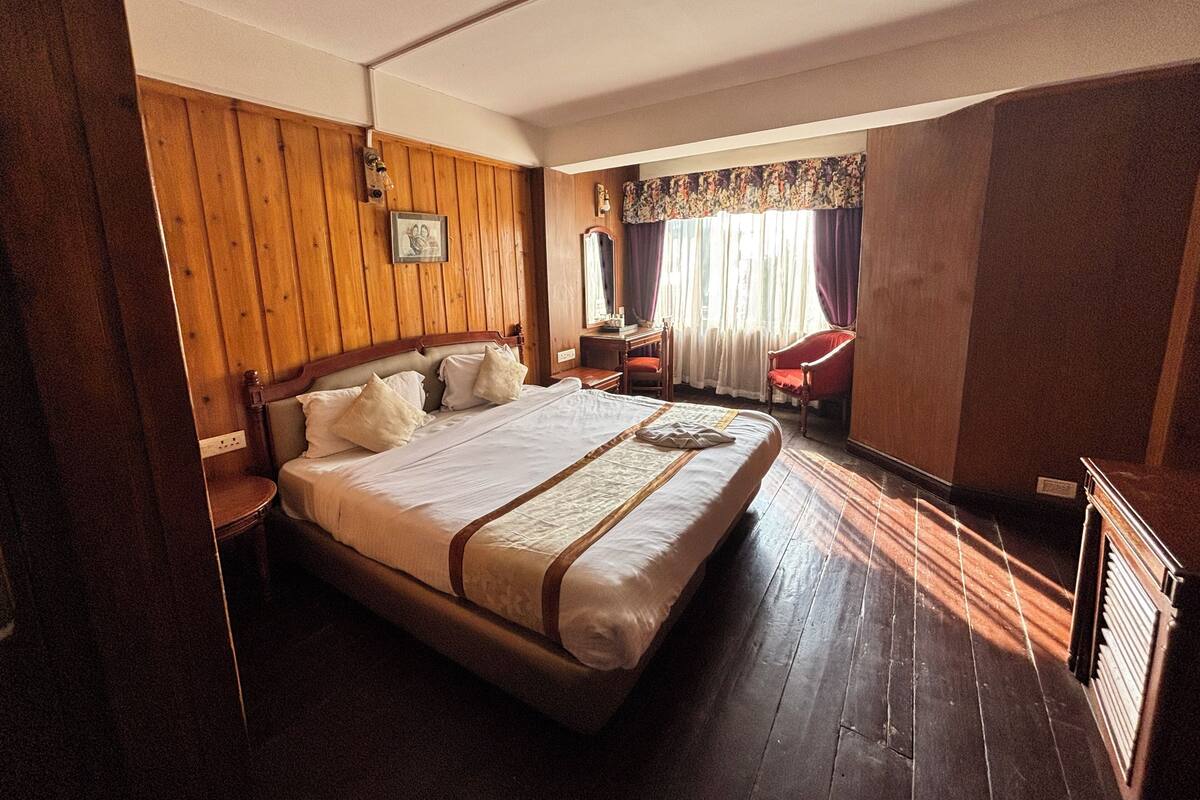 Una habitación de hotel con una cama grande, paredes de madera, un escritorio y una silla.