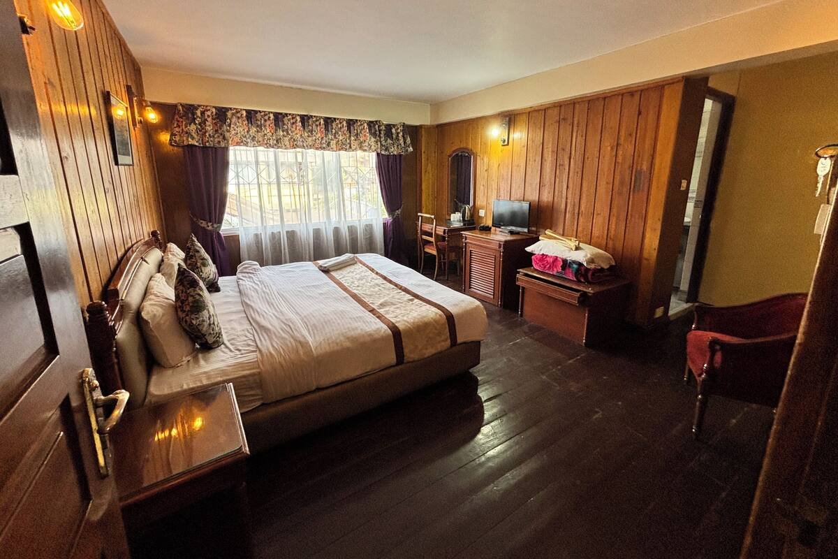 Una habitación de hotel con una cama grande, un escritorio con computadora, una silla y un armario.
