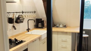 A modern kitchen with white cabinets, a black stove, and a coffee maker.