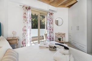 Un dormitorio con cama, mesita de noche, cómoda, espejo y ventana con cortinas.