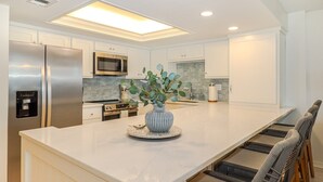 Una cocina moderna con una isla grande, electrodomésticos de acero inoxidable y un florero con hojas verdes.