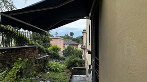A narrow alleyway with a stone wall, a metal fence, and a black awning over a doorway. - Cosy Studio Near Rapallo Beach Via Baisi (Rapallo)