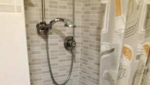A shower with a handheld showerhead, tiled walls, and a shower curtain with a pattern. - Cosy Studio Near Rapallo Beach Via Baisi (Rapallo)