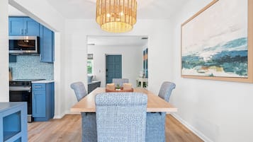 Cozinha moderna com armários azuis e área de jantar com cadeiras estampadas e mesa de madeira.