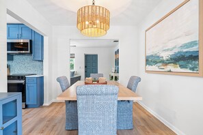 Una cocina moderna con armarios azules y un comedor con sillas estampadas y una mesa de madera.