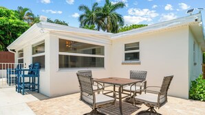 A patio with a table and chairs, a small covered area with a window, and a door. - Villa Azul | Pool + Guest House | Northwood Hills (West Palm Beach)