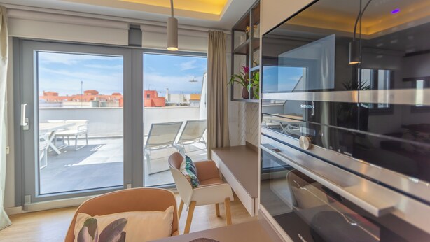 A modern living room with a large TV, a sofa, and a dining area with chairs and a table. - Penthouse Central: swimming pool terrace parking parking sea view (Tarifa)