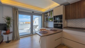 A modern kitchen with a central island, built-in appliances, and a view to the outside. - Penthouse Central: swimming pool terrace parking parking sea view (Tarifa)